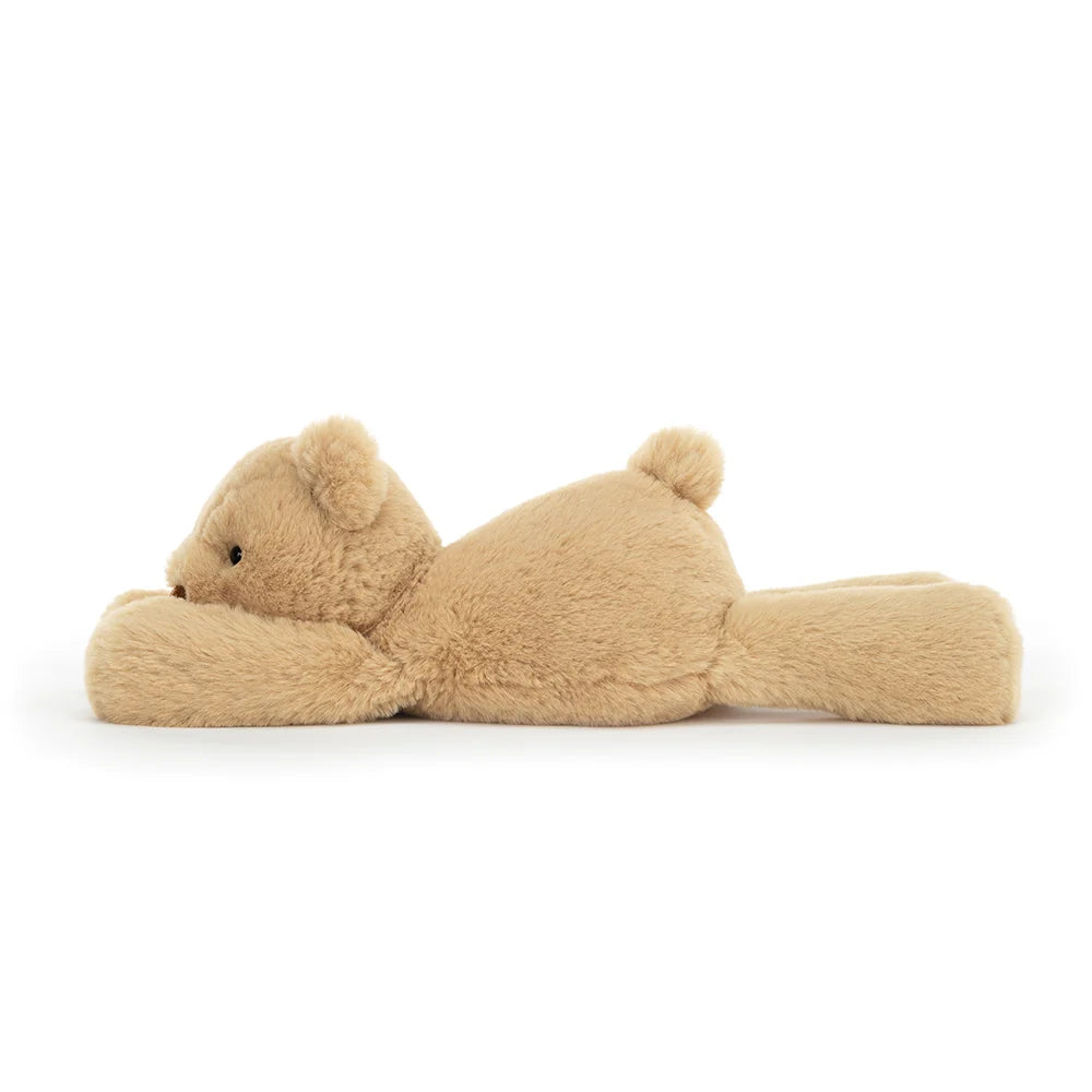 Side view: The perfect cuddle companion! This soft Jellycat plush, Smudge Bear, features honey-colored fur, podgy paws for big hugs, and a peaceful expression. 