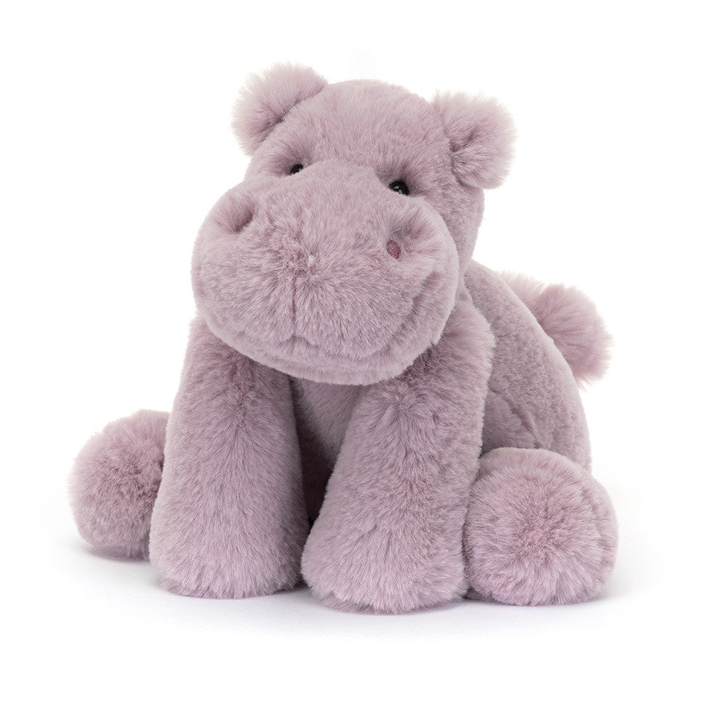 Smiling Jellycat Smudge Hippo tilted slightly, showcasing its super soft lilac fur, dainty ears, stitched nostrils, long legs, and squishy tummy.