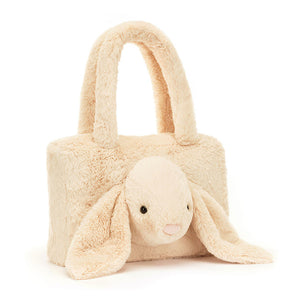 Angled View: Oatmeal-colored Jellycat Smudge Rabbit Tote Bag tilted slightly, showcasing its adorable lop-eared bunny design, soft oatmeal fur, and comfy fuzzy handles