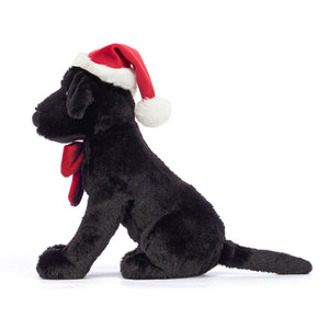 Side: Soft Jellycat Winter Warmer Pippa Lab (side view): Black Labrador plush with red bow, fleece hat & sitting alertly.