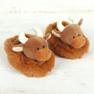 Babys slippers in the shape of fuzzy, fluffy brown Scottish Highland Cows. They are decorated with soft plush little horns on top of their heads.