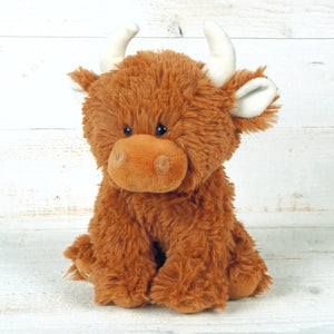 Image of the Scottish Highland Cow Children's plush soft toy against a wooden background.