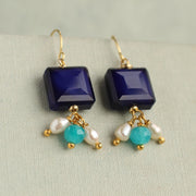 Front view of Lapis Lazuli blue charm earrings with square navy glass stones and dangling turquoise, aqua opal glass, and freshwater pearl charms on gold hooks.