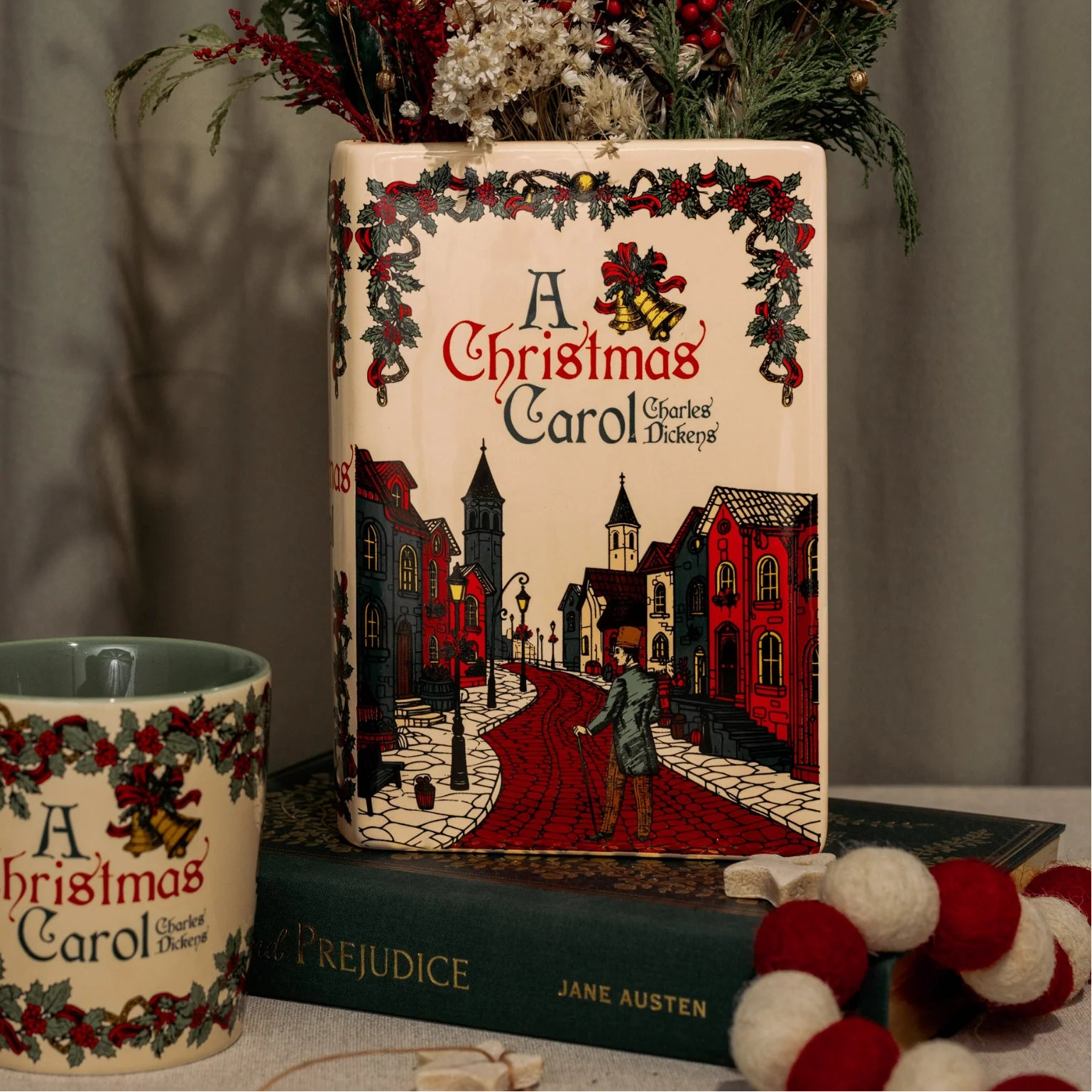 Styled scene with A Christmas Carol vase filled with dried flowers and matching mug.
