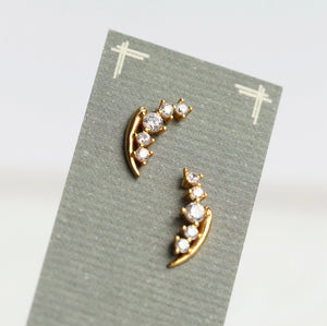 Flat-lay image of lily of the valley earrings displayed on a textured card, highlighting the gold vermeil finish and dainty crystal flowers in soft lighting.