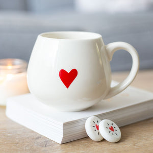 Picture of the Love Heart Hidden Message Mug sitting on top of a stack of paper. 