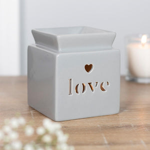 Love Oil Burner set on a table top with a candle burning inside.