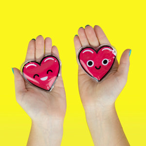 Pair of red heart-shaped reusable hand warmers held in hands