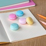 Macaron erasers in pastel colours on notebook with pencils and pencil case