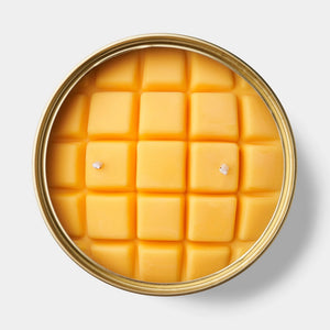 Top view of Mango Bowl candle featuring vibrant yellow wax shaped into square mango cubes with two cotton wicks, set in a round metal tin.
