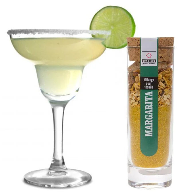 Margarita cocktail in a glass with lime alongside Margarita cocktail mix bottle.