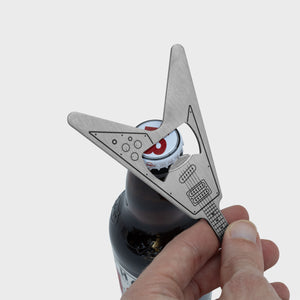 Close-up of hand using flying V guitar-shaped bottle opener to open a capped beer bottle.