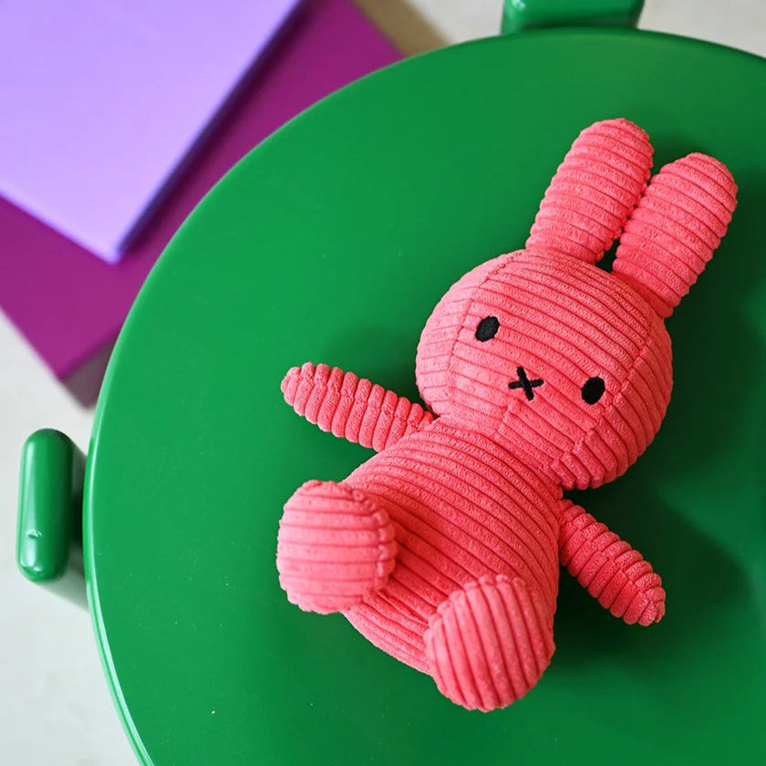 Miffy Eco Corduroy Fuchsia plush toy placed on a green stool with colourful blocks in the background.