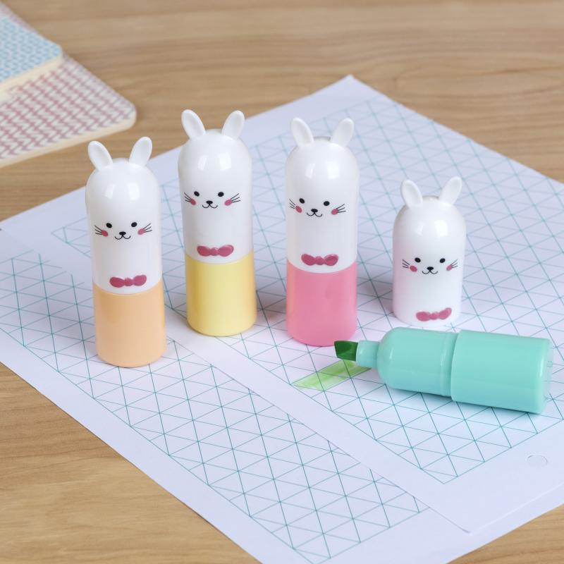 Bunny highlighters standing on grid paper on wooden desk