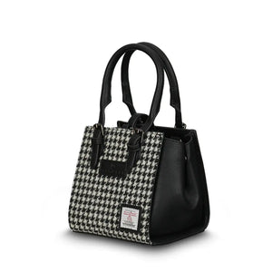 Islander Mini Caillie Tote in black and white dogtooth Harris Tweed, viewed from the side with a folded silhouette.