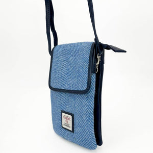 Side angle of Harris Tweed mini crossbody bag with adjustable navy strap and zipped top compartment.
