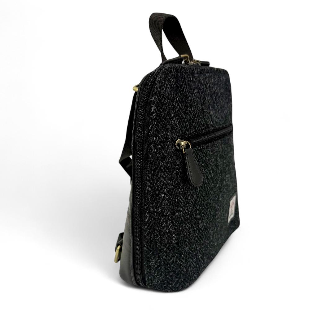 Charcoal Harris Tweed mini backpack side view showing zip pocket on white background.