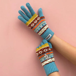 Blue Moomin Fair Isle gloves on hands against a pink background.