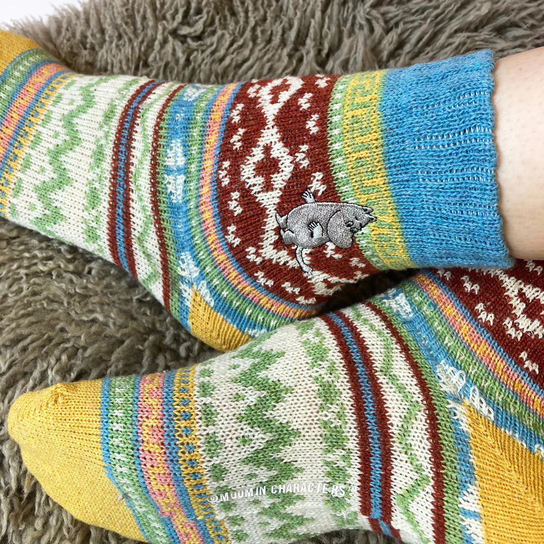 Close-up of Moomin embroidery detail on Fair Isle knit socks in blue, red, and green.