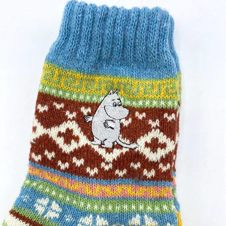 Detailed view of the Moomin character embroidered on the ankle of a Fair Isle sock with blue cuff.