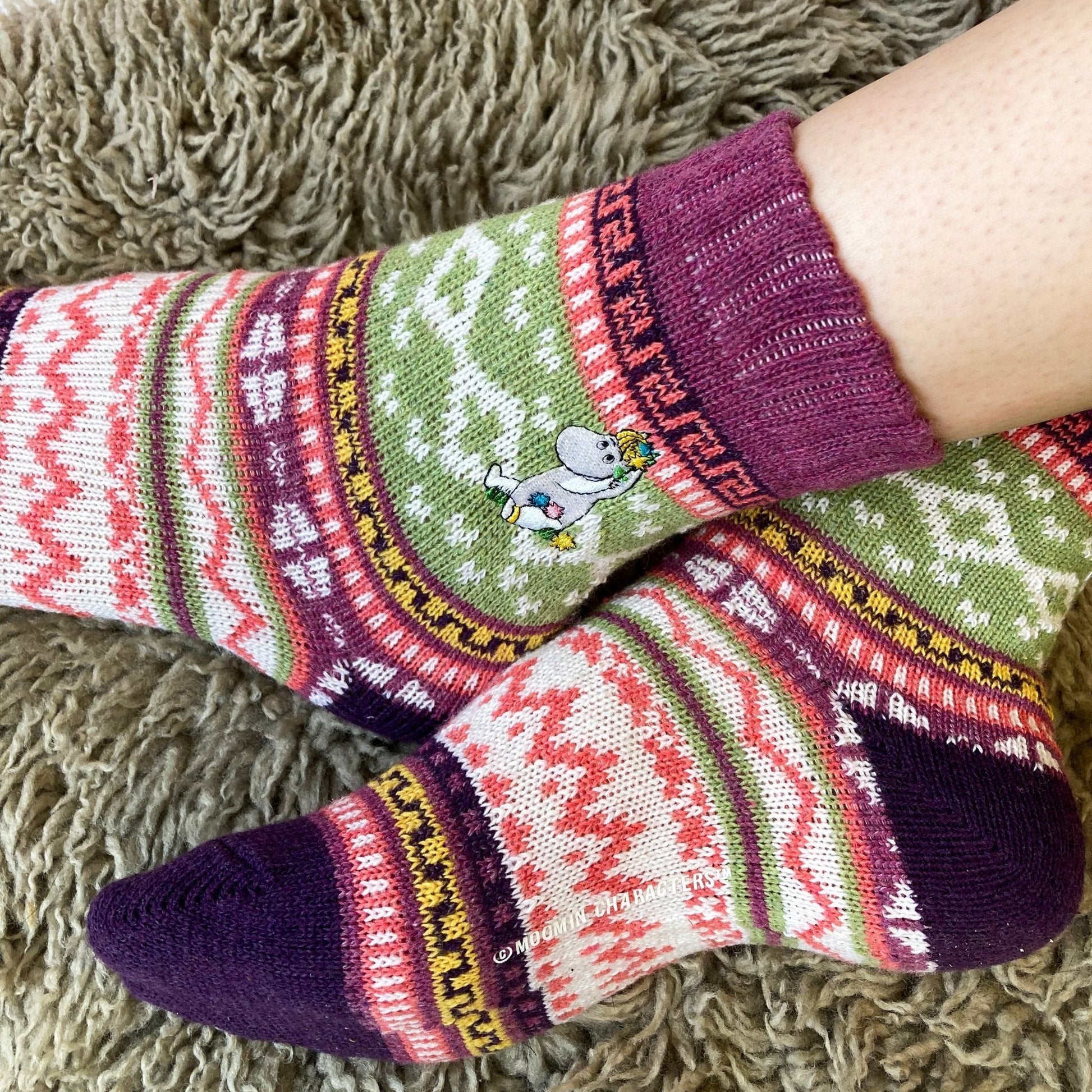 Cosy close-up of feet wearing Snorkmaiden socks on fluffy rug.