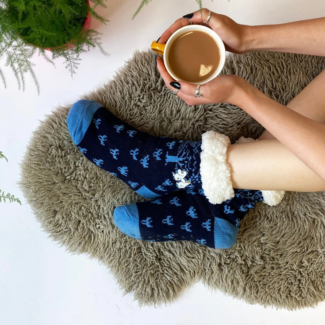 Moomin Forest Slipper Socks worn with fleece cuffs, held cup of tea