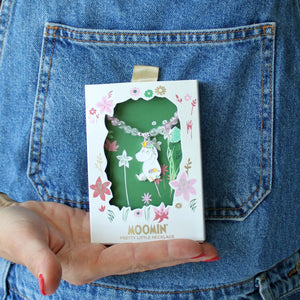 Image 5: A person wearing denim holding the boxed Moomin Snorkmaiden Enamel Necklace, displaying its charming floral packaging.