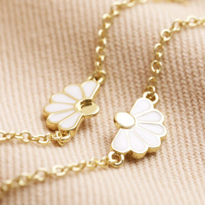 Close-up of gold-plated daisy charm with white enamel details.