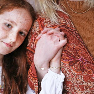 Mother and daughter wearing their matching gold flower bracelets together.