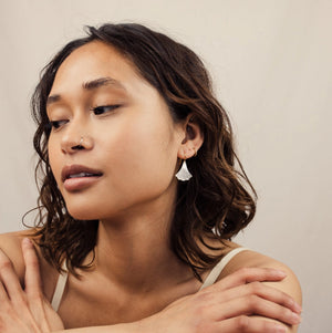 A woman wearing the Mother of Pearl Art Deco earrings, highlighting their elegant dangle just below the earlobe.