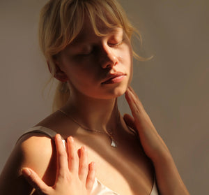 Soft-lit portrait of a model wearing the gold-plated Mother of Pearl fan necklace.