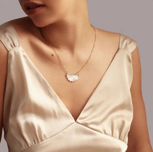 Model wearing the Mother of Pearl Scallop Necklace – A woman in a satin dress wearing an elegant Mother of Pearl scallop pendant necklace, highlighting its Art Deco-inspired design.