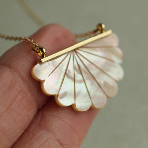 Close-up of a Mother of Pearl Scallop Necklace – A delicate scallop-shaped pendant made of luminous Mother of Pearl, set in a gold-tone frame, displayed on a fine gold chain.