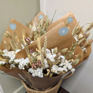 A rustic-inspired dried flower bouquet in soft neutral tones, wrapped and ready for display.