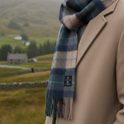 Navy and beige tartan lambswool scarf with fringed edges neatly folded.