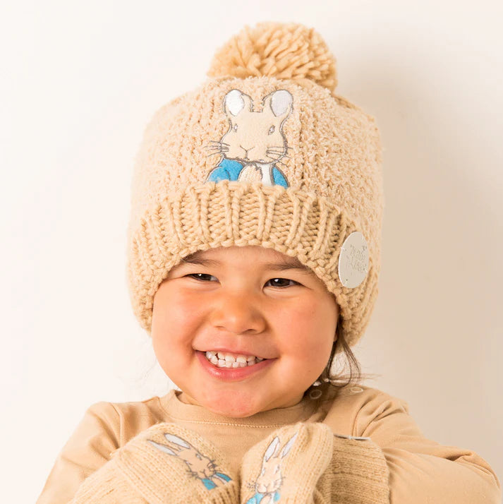 Smiling child wearing neutral Peter Rabbit™ winter hat and matching gloves – cosy fleece-lined kids beanie with Peter Rabbit embroidery.