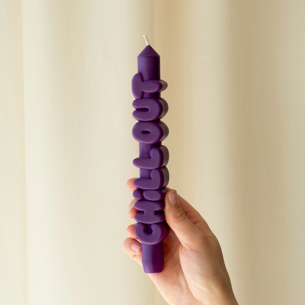 Hand holding the indigo Chill Out taper candle showing its sculptural shape and unscented wax finish, designed to make a bold statement.