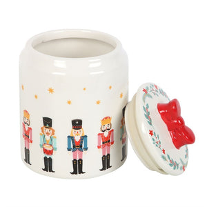 Open ceramic nutcracker Christmas storage jar with decorative red bow lid placed to the side, showing interior space for biscuits or sweets.