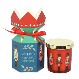 Festive Nutcracker candle and gift box with red ribbon and gold lid.