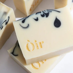 Close-up of Òir soap bar showcasing black swirl design, gold foil branding and creamy finish.