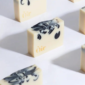 Stylish cedarwood and geranium soap bars with intricate black marbling and Òir gold branding.
