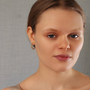 A woman wearing the olive branch gold hoop earrings, showcasing their elegant and delicate design.