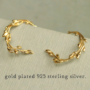 Close-up of the gold olive branch hoop earrings on a presentation card, highlighting their intricate details.