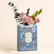 Mini ceramic book-shaped vase with “Once Upon A Time” design holding dried flowers.