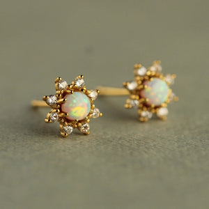 Angled side view of delicate opal flower stud earrings, featuring glowing white opals and gold-plated floral settings with cubic zirconia accents.