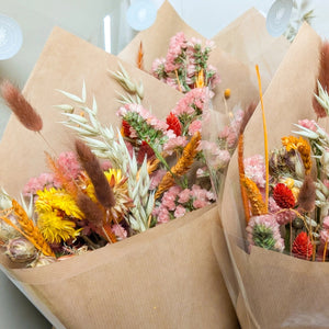 Elegant dried floral bouquet featuring wheat stems, grasses, and delicate wildflowers in autumnal shades.