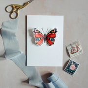 Front image of Peacock Butterfly Pop Out Card with 3D wings and stationery props.