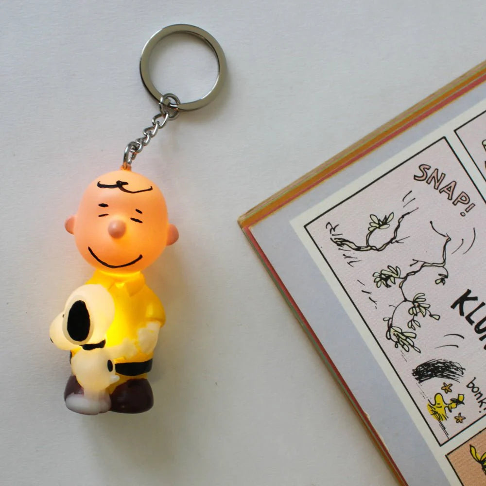 Charlie Brown keyring illuminated, showing light-up feature near comic book.