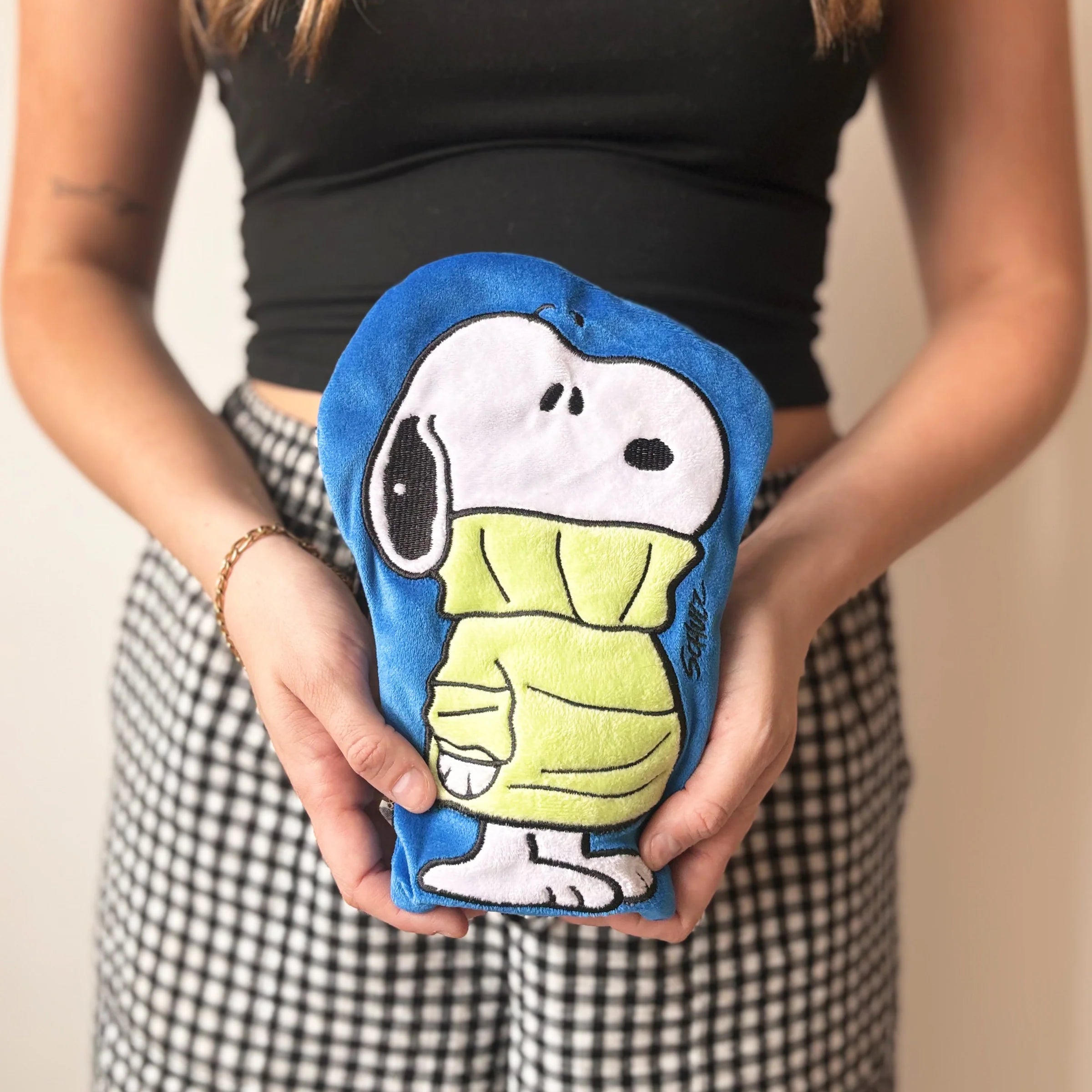 Woman holding Peanuts Snoopy Jumper mini hot water bottle in hands.