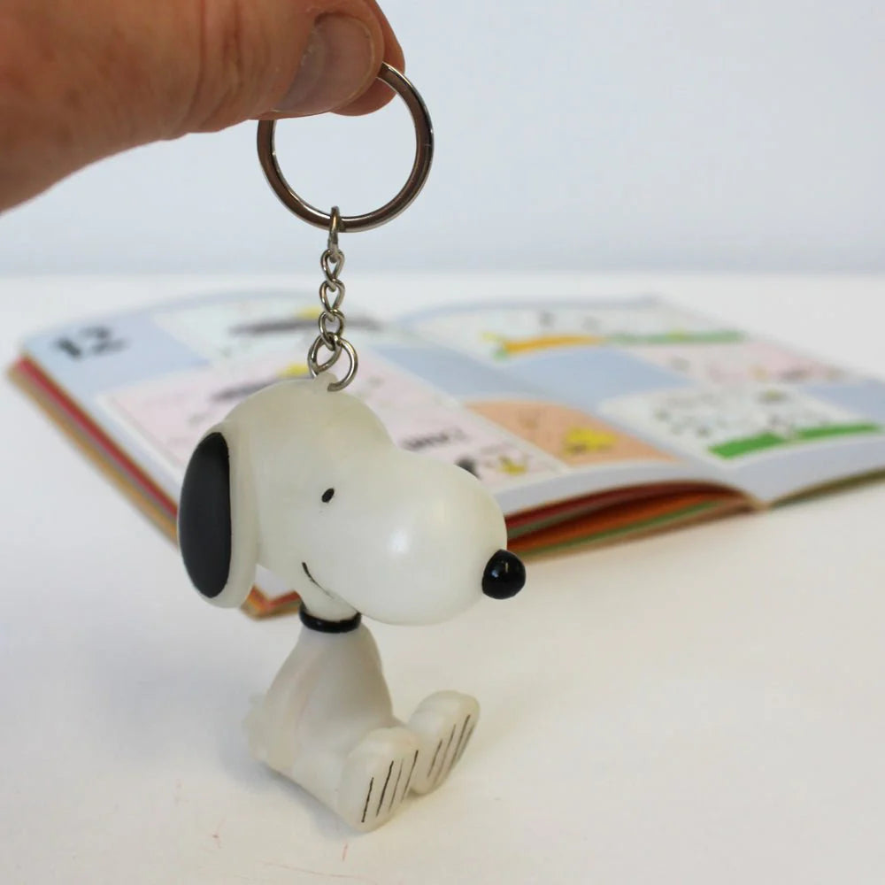 Hand holding the Snoopy keyring, showcasing its compact design.
